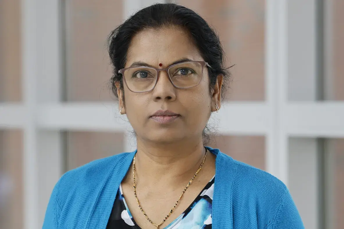 portrait of Manjula Karpurapu wearing a blue sweater and glasses